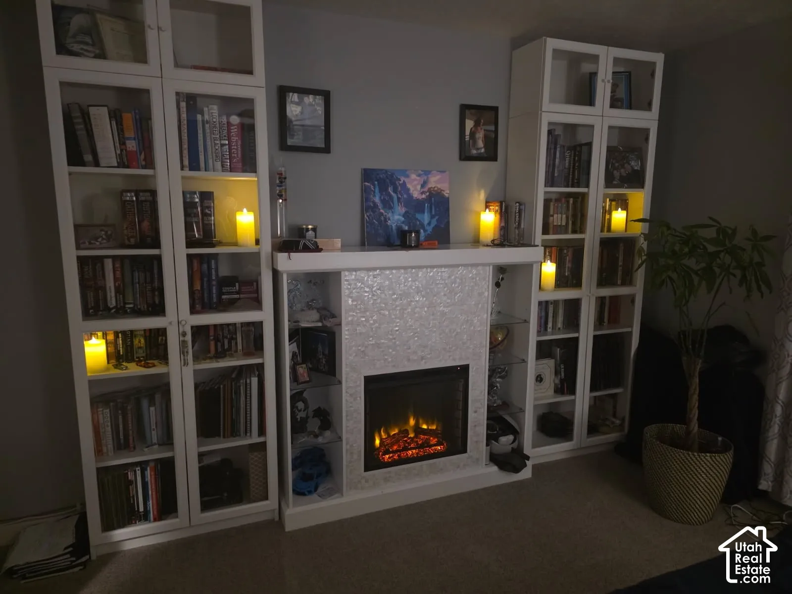 Built-in shelving units, integrated electric fireplace with a decorative tile surround, and a light-colored wall finish