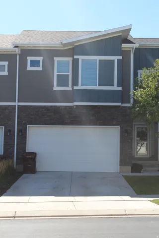 Contemporary exterior featuring a two-car garage, stone veneer, and a gray siding facade