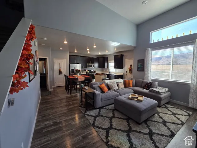 Open-concept living space with wood-finish flooring, recessed lighting, and a high ceiling