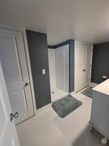 White paneled doors, built-in shower stall, overhead lighting, and vanity with countertop