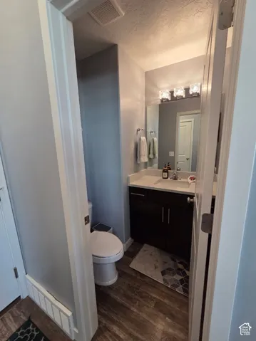 Wood-finish flooring, dark wood vanity with white countertop, integrated sink, and modern vanity lighting