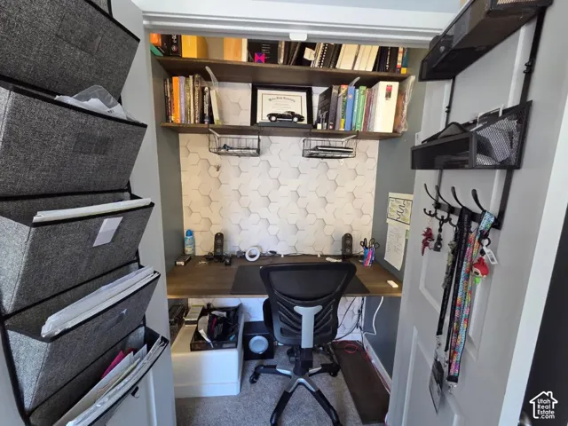 Built-in desk with overhead shelving, hexagonal wall detailing, and carpeting