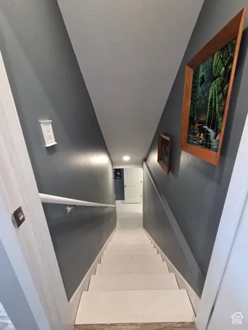Interior staircase with a white handrail, recessed lighting, and a neutral wall color