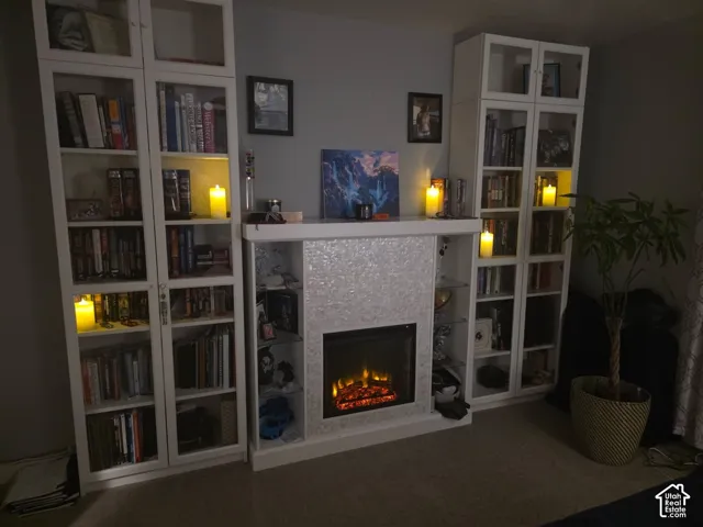 Electric fireplace with a textured surround, flanked by two built-in shelving units featuring glass-front doors