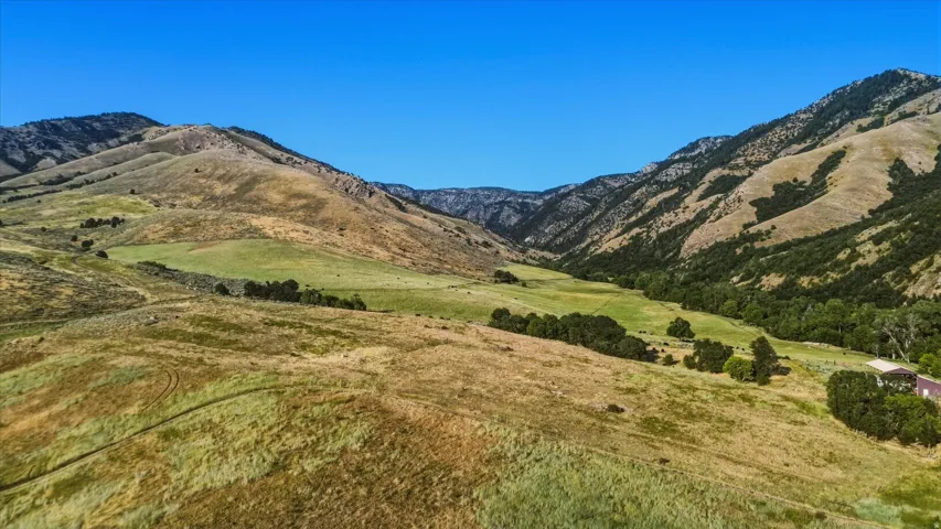 Expansive mountainous terrain with verdant valleys and scattered trees