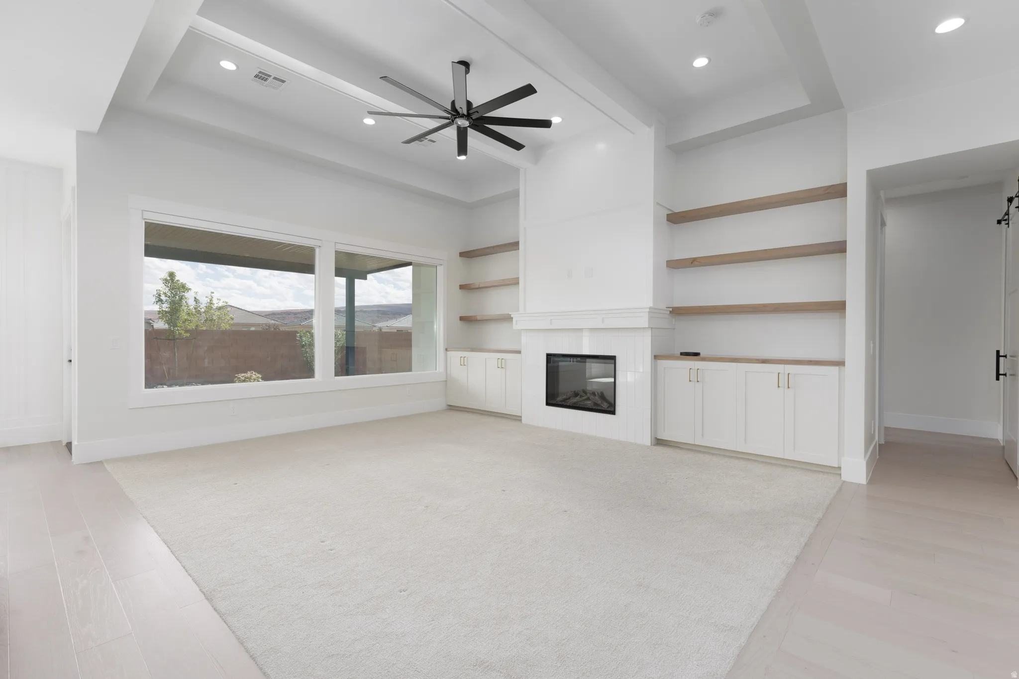 Recessed lighting, a tray ceiling, and a ceiling fan illuminate this space