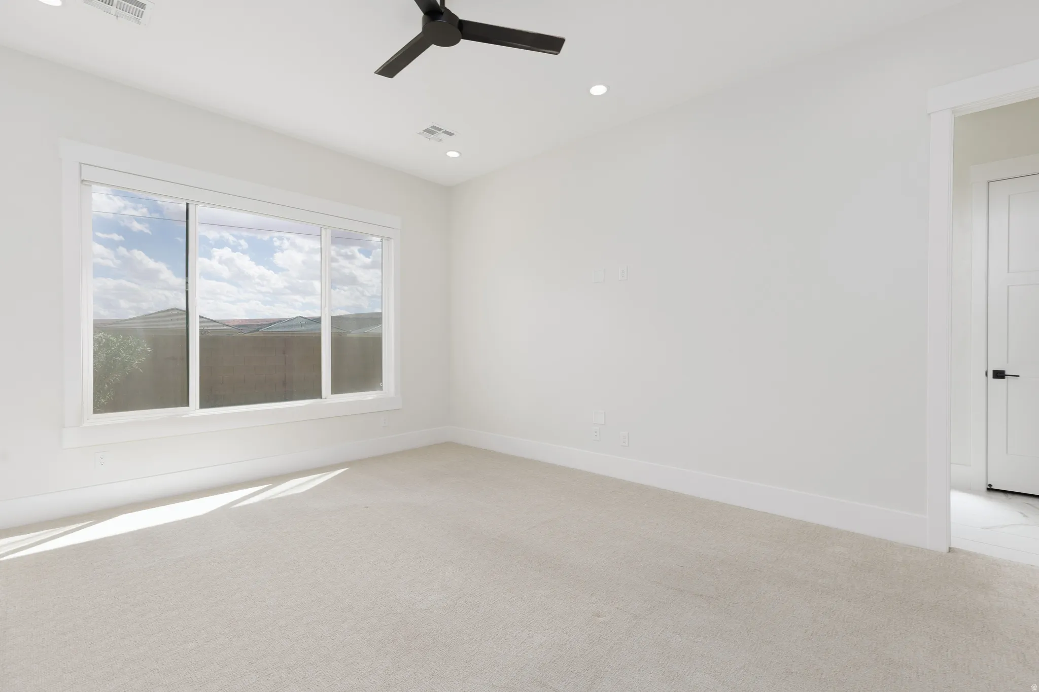 Expansive window with mountain backdrop, recessed lighting, ceiling fan, neutral carpeting, and a modern interior door