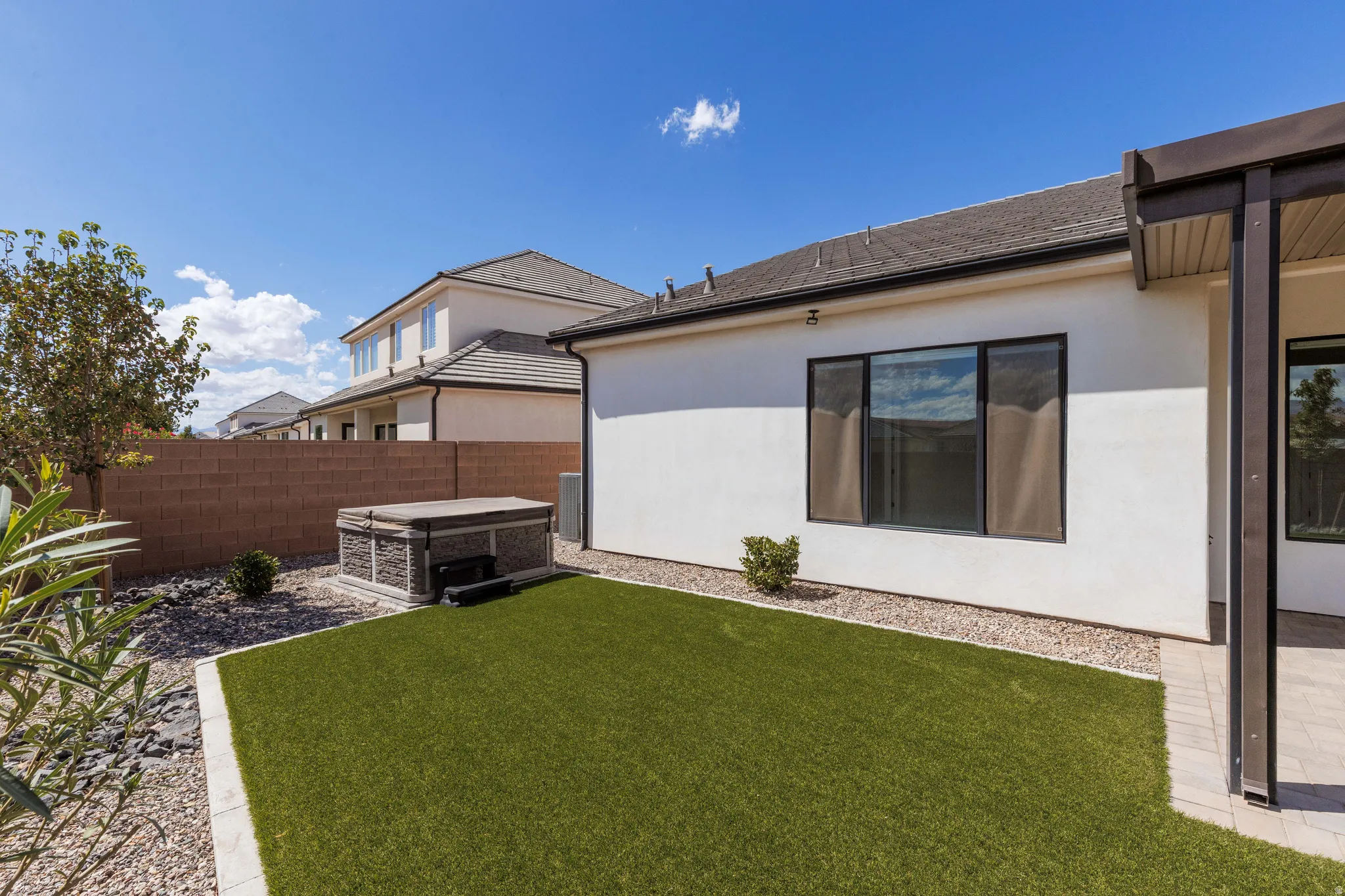 Backyard featuring artificial turf, a privacy wall, gravel landscaping, and an attached patio cover