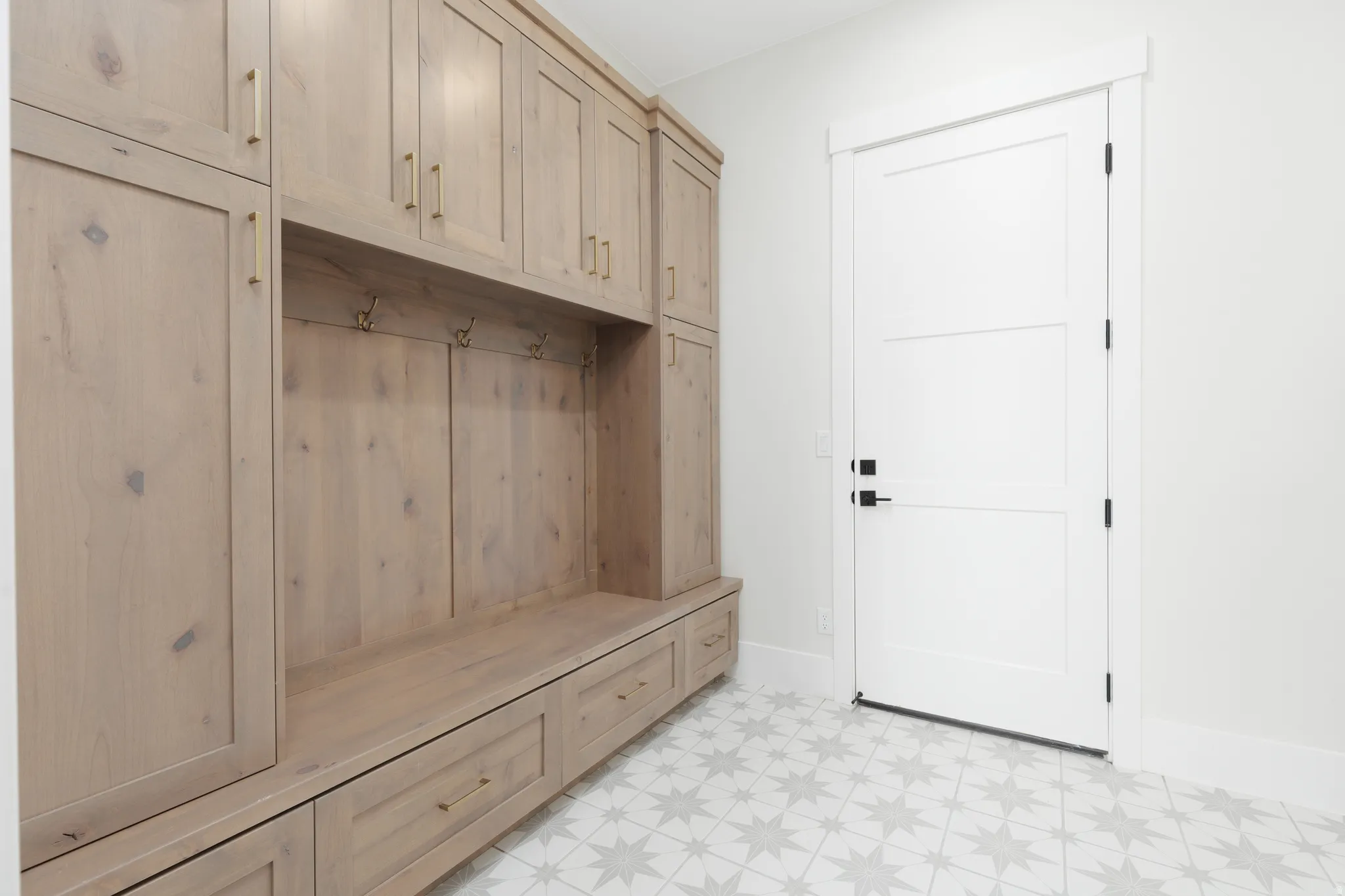 Built-in wood-finish cabinetry featuring a bench, storage drawers, and coat hooks