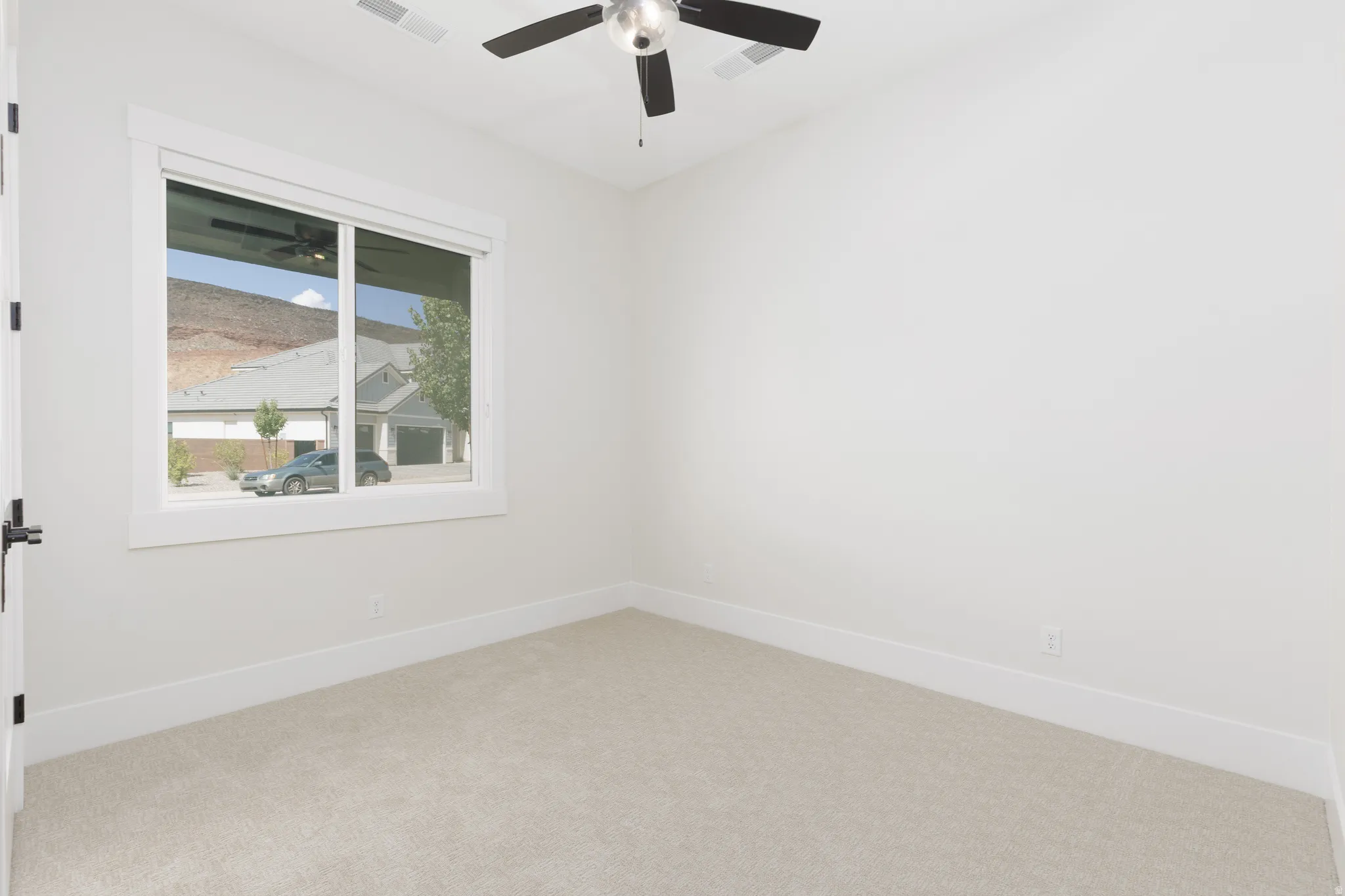 Neutral wall color, carpeted flooring, white trim, ceiling fan light fixture, and a window with mountain scenery