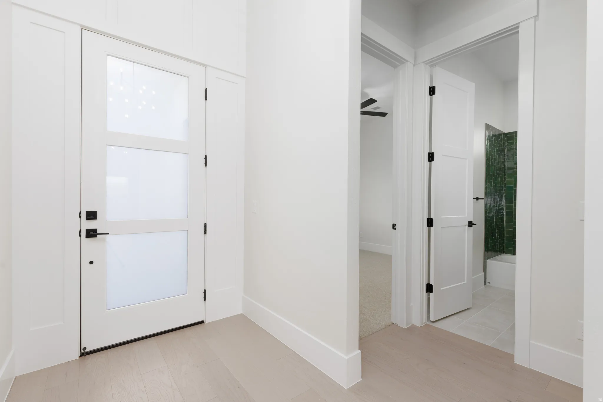 Entryway with wood-finish flooring, a contemporary white door with three frosted glass panels, and matte black hardware