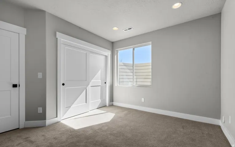 Window with horizontal blinds, recessed ceiling lighting, carpet flooring, and white paneled sliding closet doors