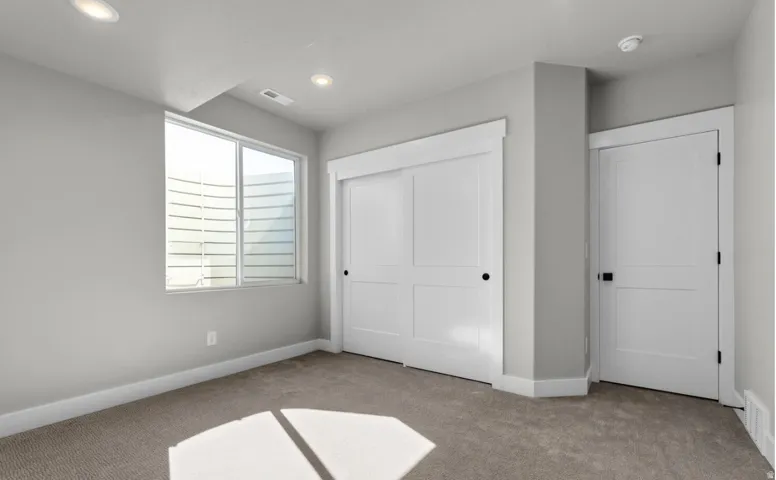 Recessed ceiling lighting, carpet flooring, a window with a light well, and solid core doors