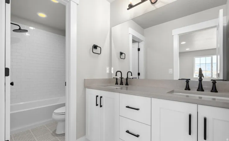 Dual sink vanity with matte black fixtures and white cabinetry, integrated stone-finish countertop, and a full-width mirror