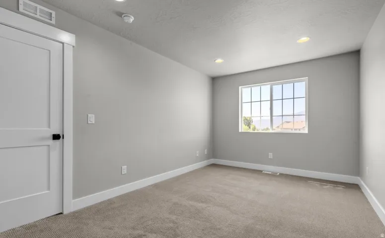 Recessed lighting, light gray wall finish, carpeted flooring, white trim, and a white paneled door with black hardware
