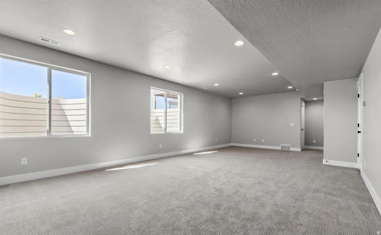 Spacious room with gray wall-to-wall carpeting, recessed lighting, and light gray painted walls