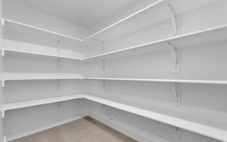 Built-in shelving with white finishes, wall-mounted brackets, and a light-colored carpeted floor