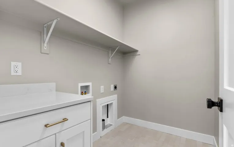 White shaker-style cabinetry with gold-finish hardware, a white countertop, and integrated shelving