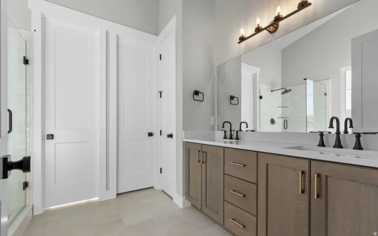 Dual vanity with white countertops, wood-finish cabinetry, and matte black fixtures