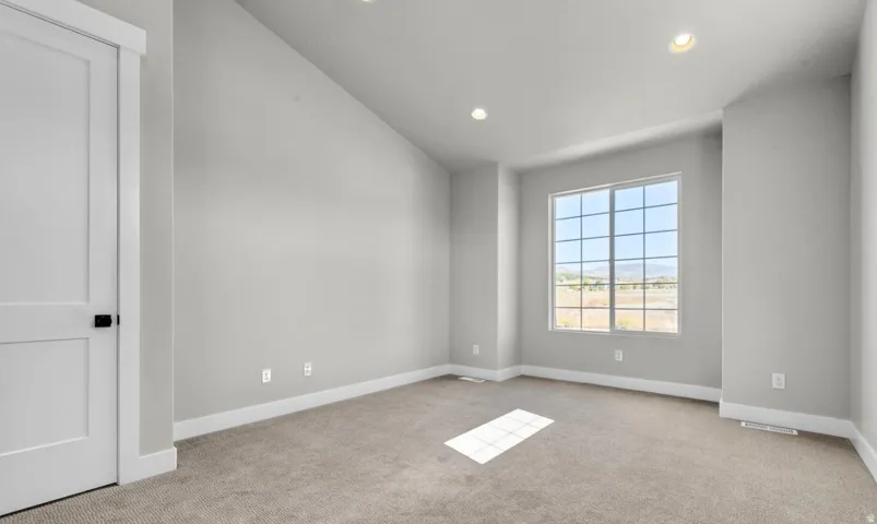 Vaulted ceiling, recessed lighting, carpet flooring, large grid window, and a white paneled door