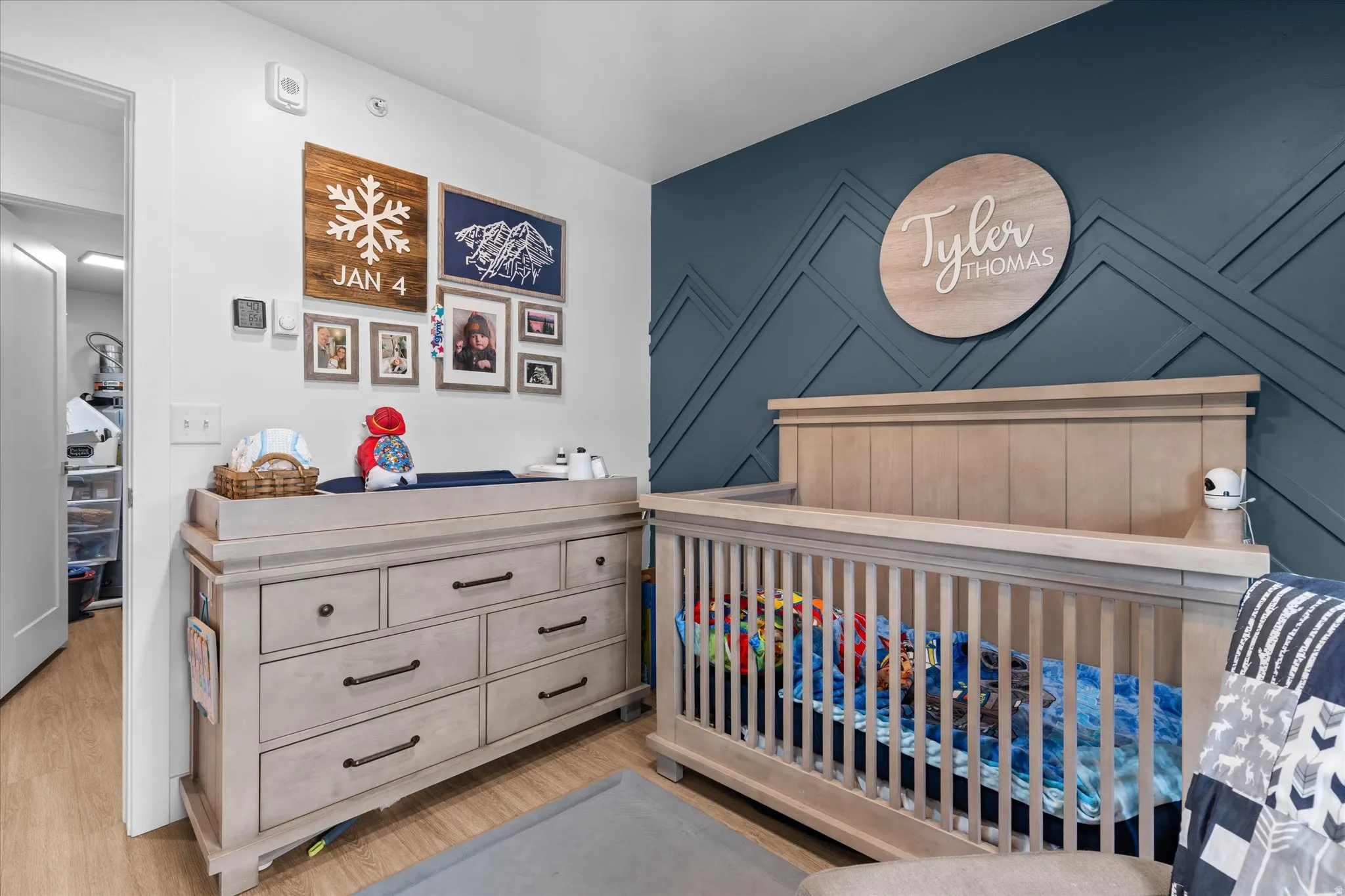 Accent wall with geometric paneling, wood-finish flooring, recessed lighting, and a white interior door
