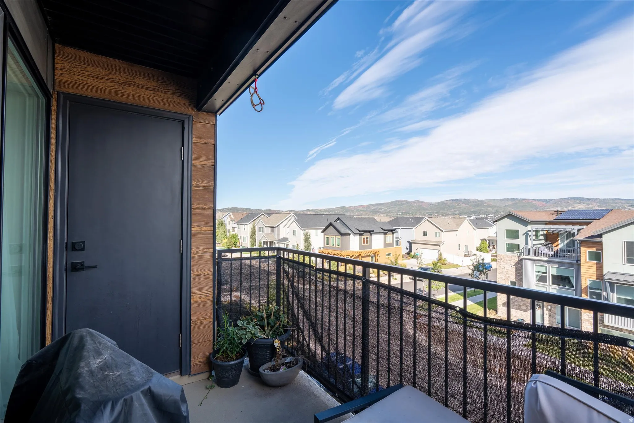 Balcony with mountain range backdrop, black metal railing, and textured exterior wall