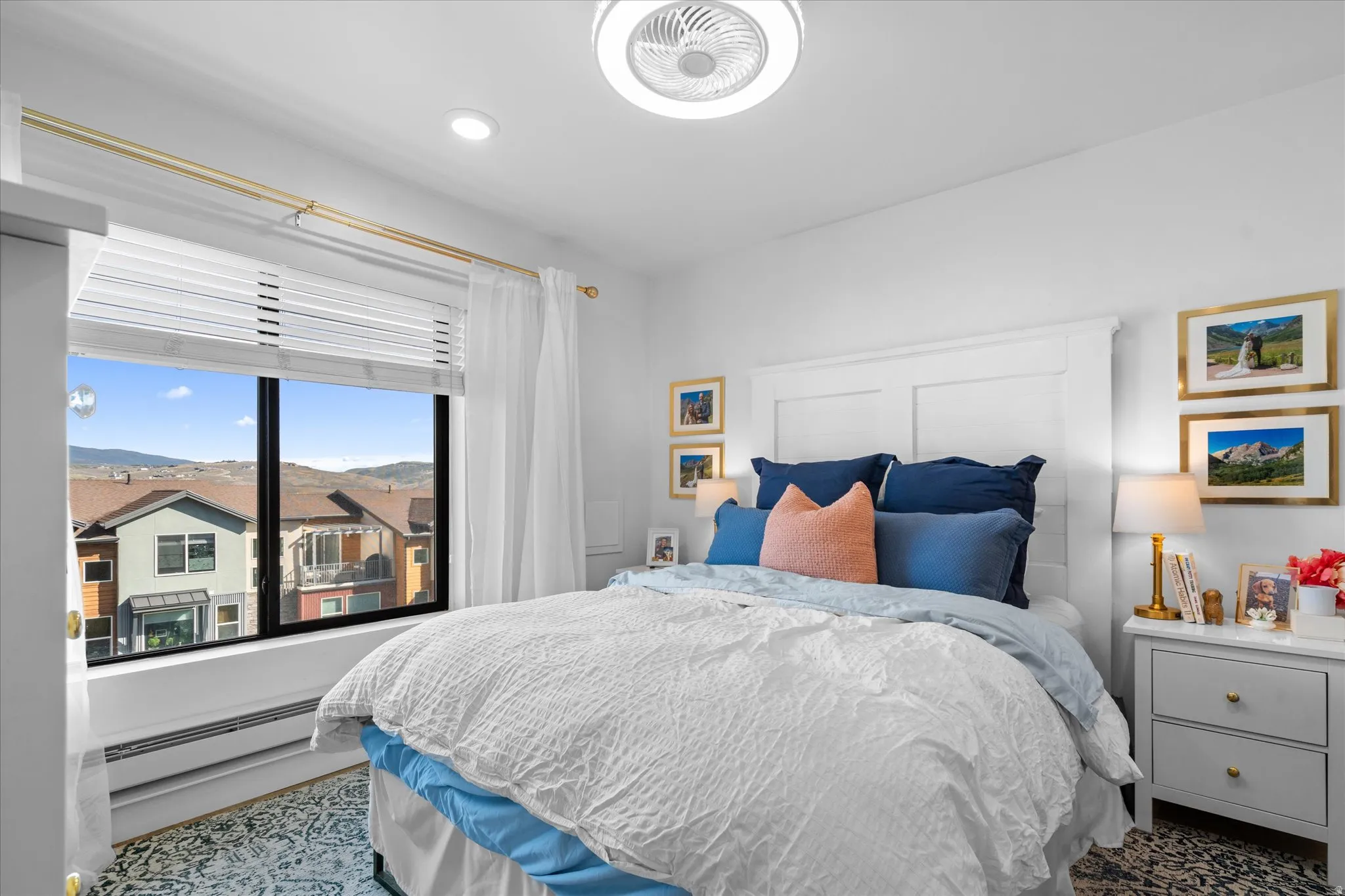 Spacious bedroom featuring an expansive window, built-in headboard, recessed lighting, and a ceiling fan