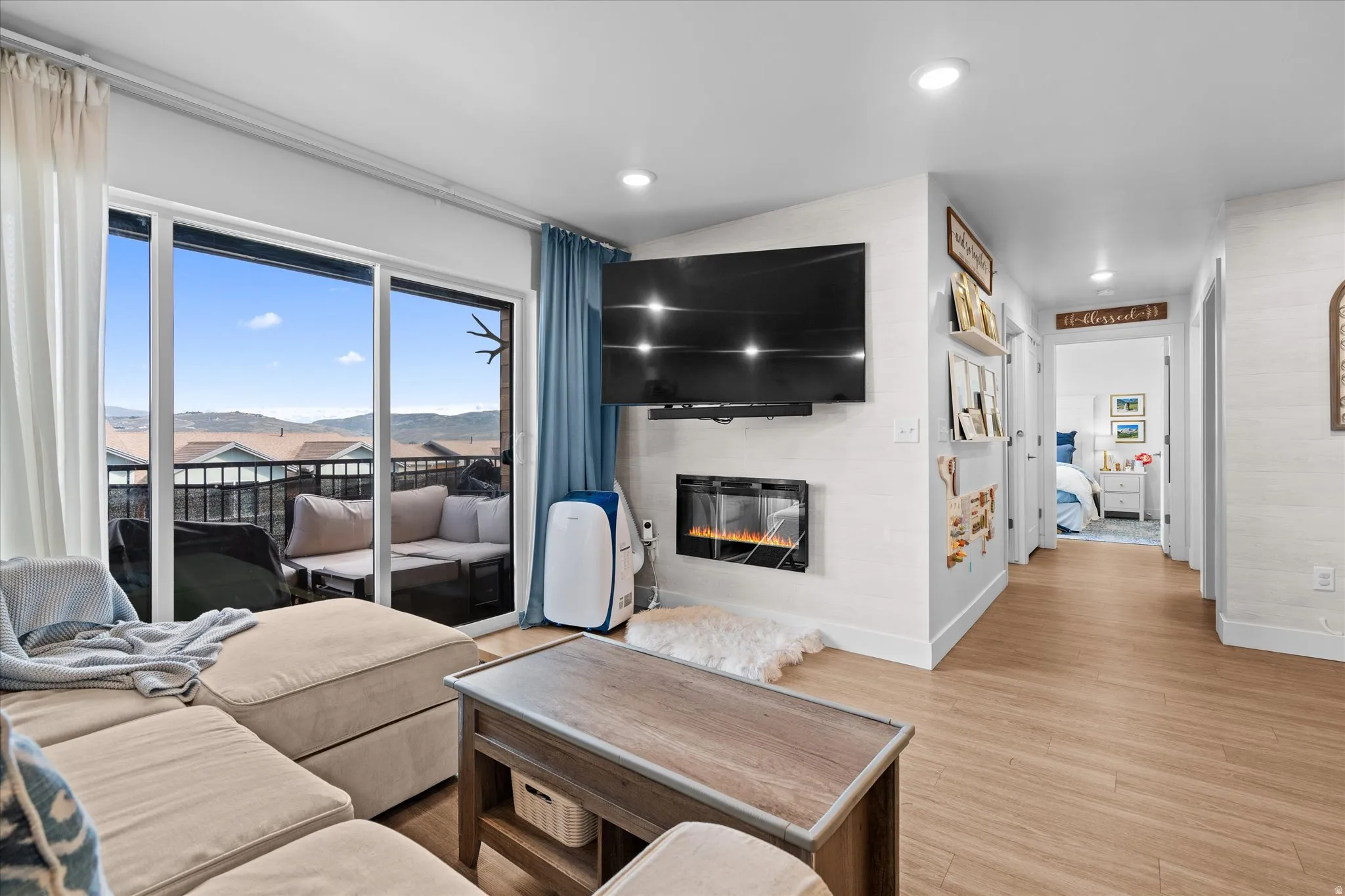 Sliding glass door to balcony, recessed lighting, wood-finish flooring, and built-in electric fireplace
