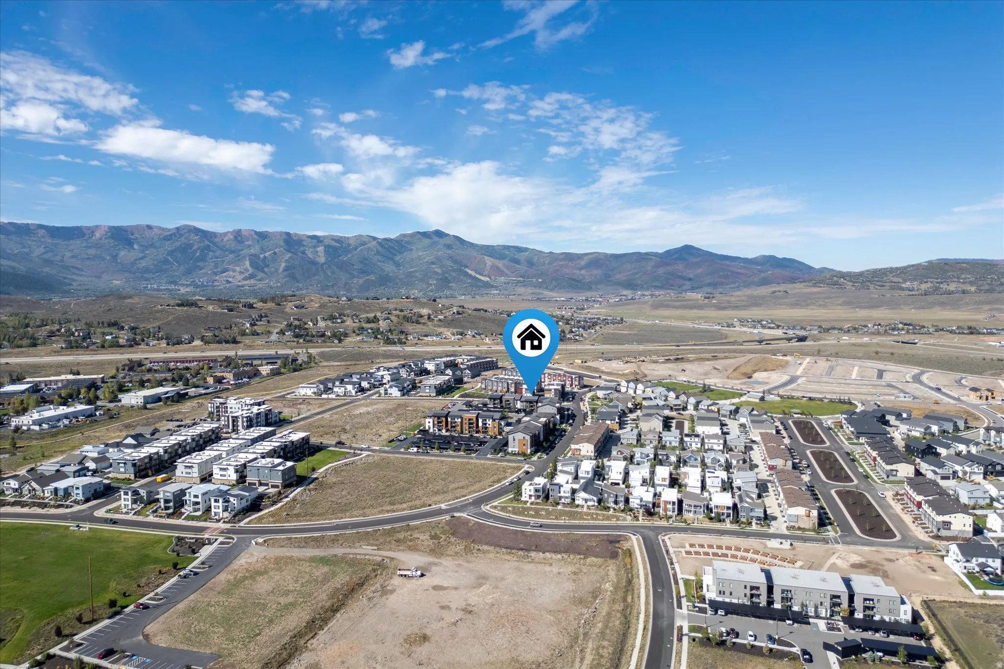 Expansive mountain backdrop with a developed residential area featuring multiple housing styles and a clear road network