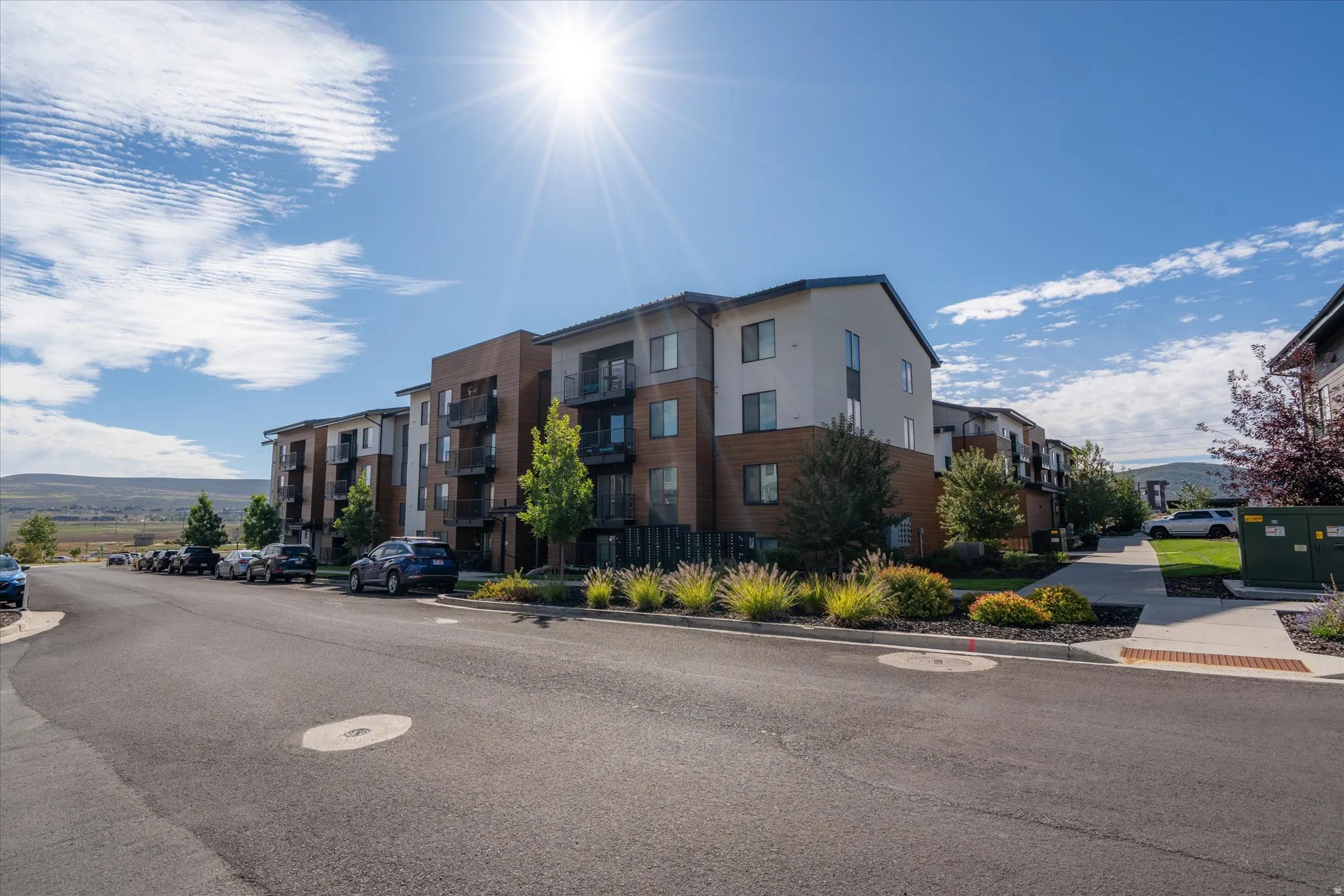 Multi-story building with a stucco and wood-finish facade, private balconies, and landscaped grounds