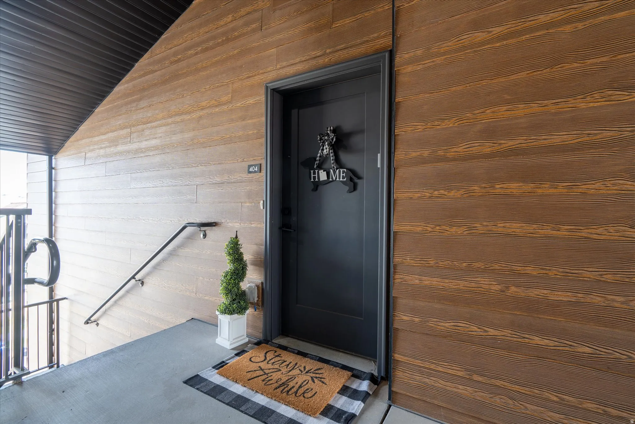 Dark-paneled entry door, wood-finish siding, and a sloped metal roof overhang