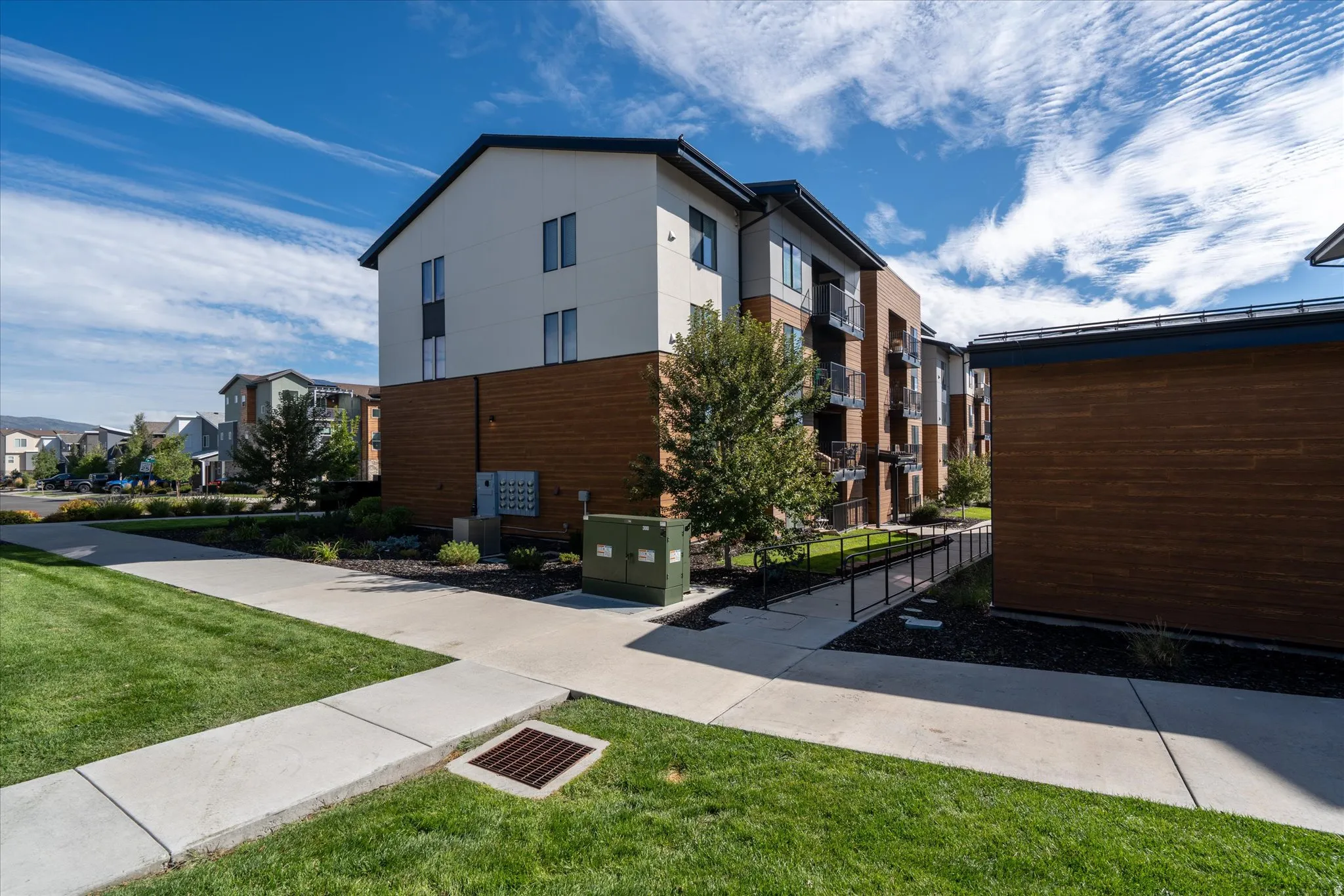 Modern multi-story building featuring light-colored siding and wood-finish accents