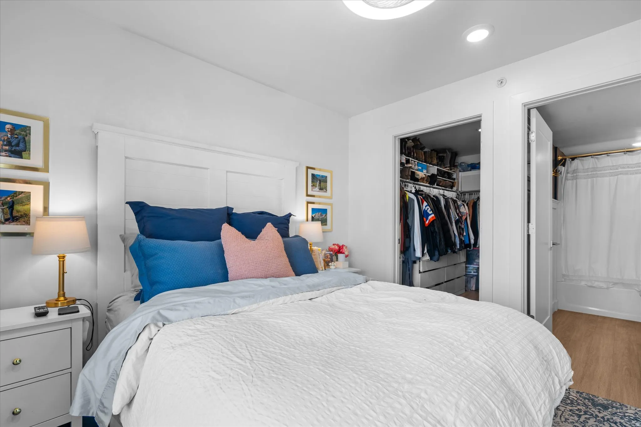 White paneled headboard, recessed lighting, built-in closet organization, light wood-finish flooring, and white interior doors