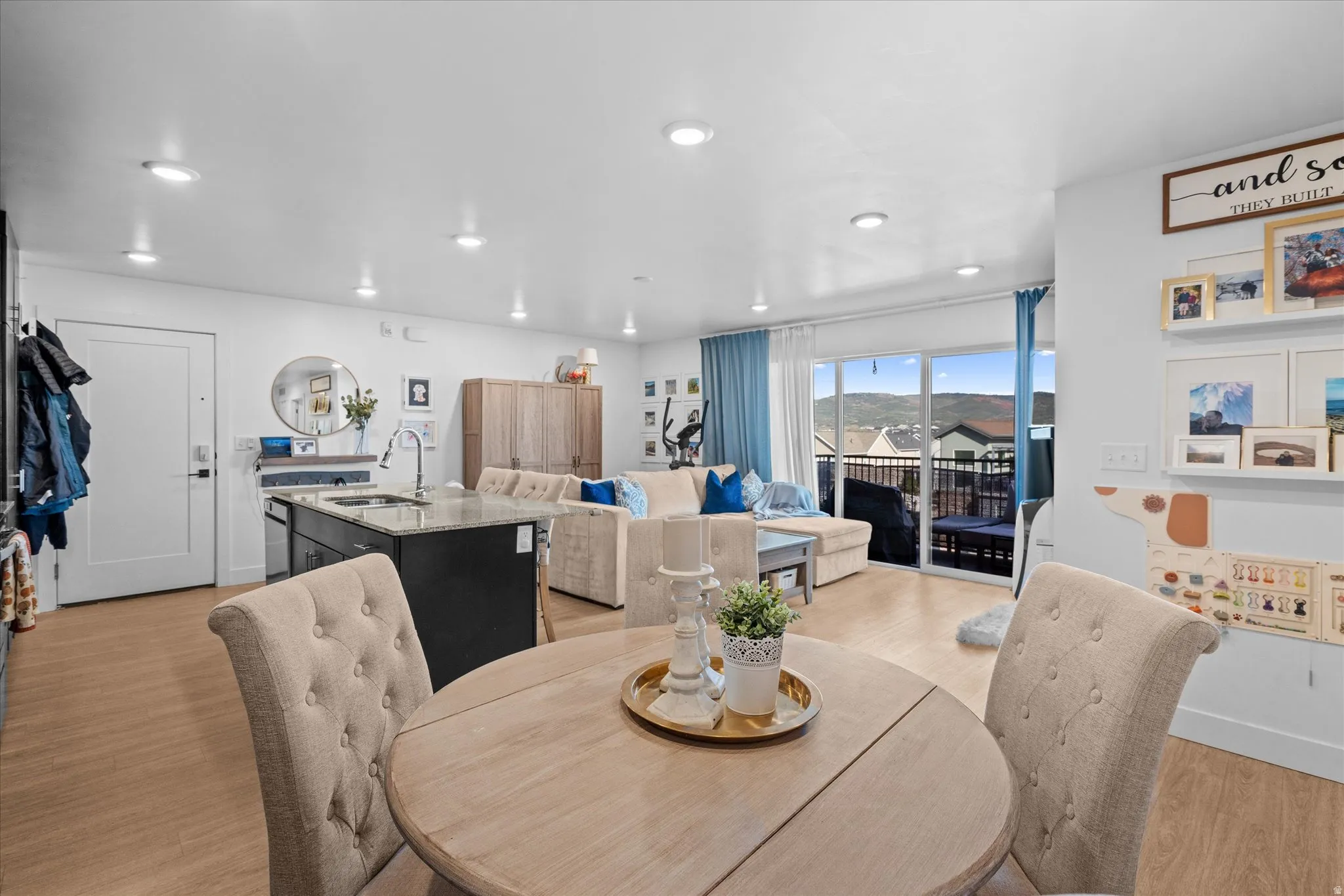 Open-concept living area featuring wood-finish flooring, recessed lighting, and a kitchen island with a stone-finish countertop
