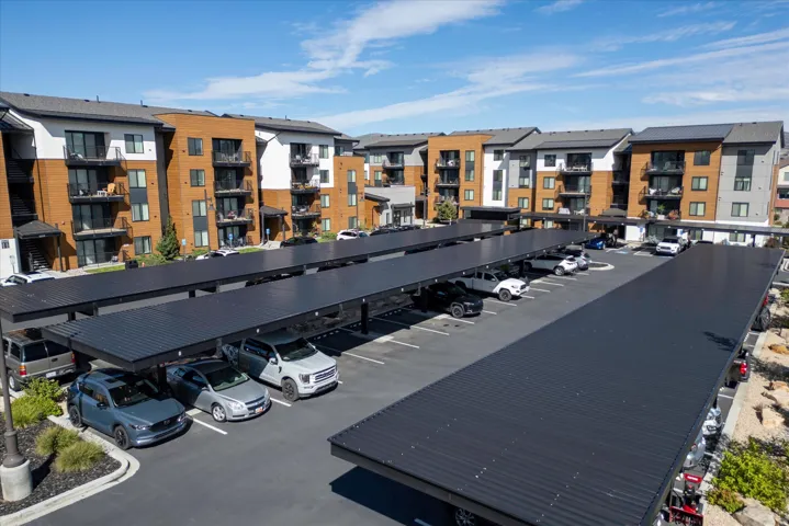 Multi-story residential buildings featuring private balconies and covered parking structures with ample spaces