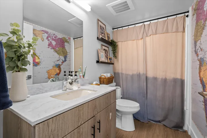 Vanity with a rectangular undermount sink, a stone-finish countertop, and wood-finish cabinetry