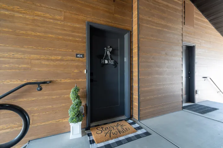 Wood-finish exterior siding, concrete walkway, and black metal handrail