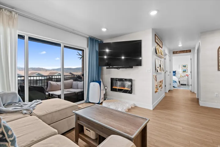 Sliding glass door to balcony, recessed lighting, wood-finish flooring, and built-in electric fireplace