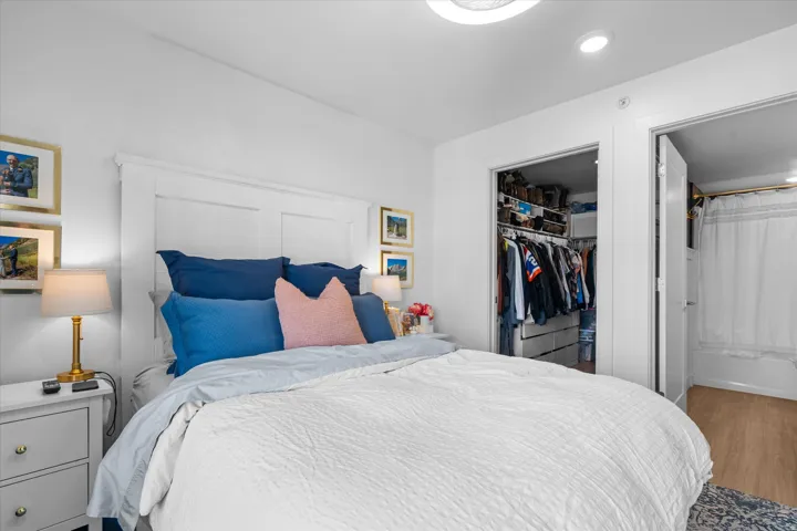 White paneled headboard, recessed lighting, built-in closet organization, light wood-finish flooring, and white interior doors