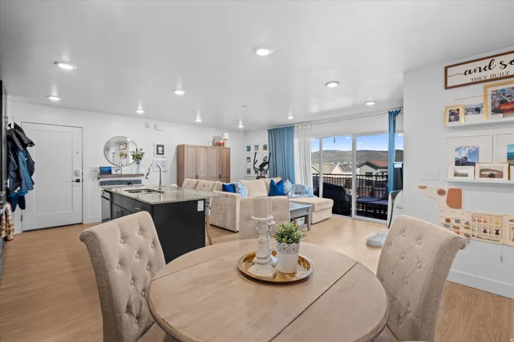 Open-concept living area featuring wood-finish flooring, recessed lighting, and a kitchen island with a stone-finish countertop