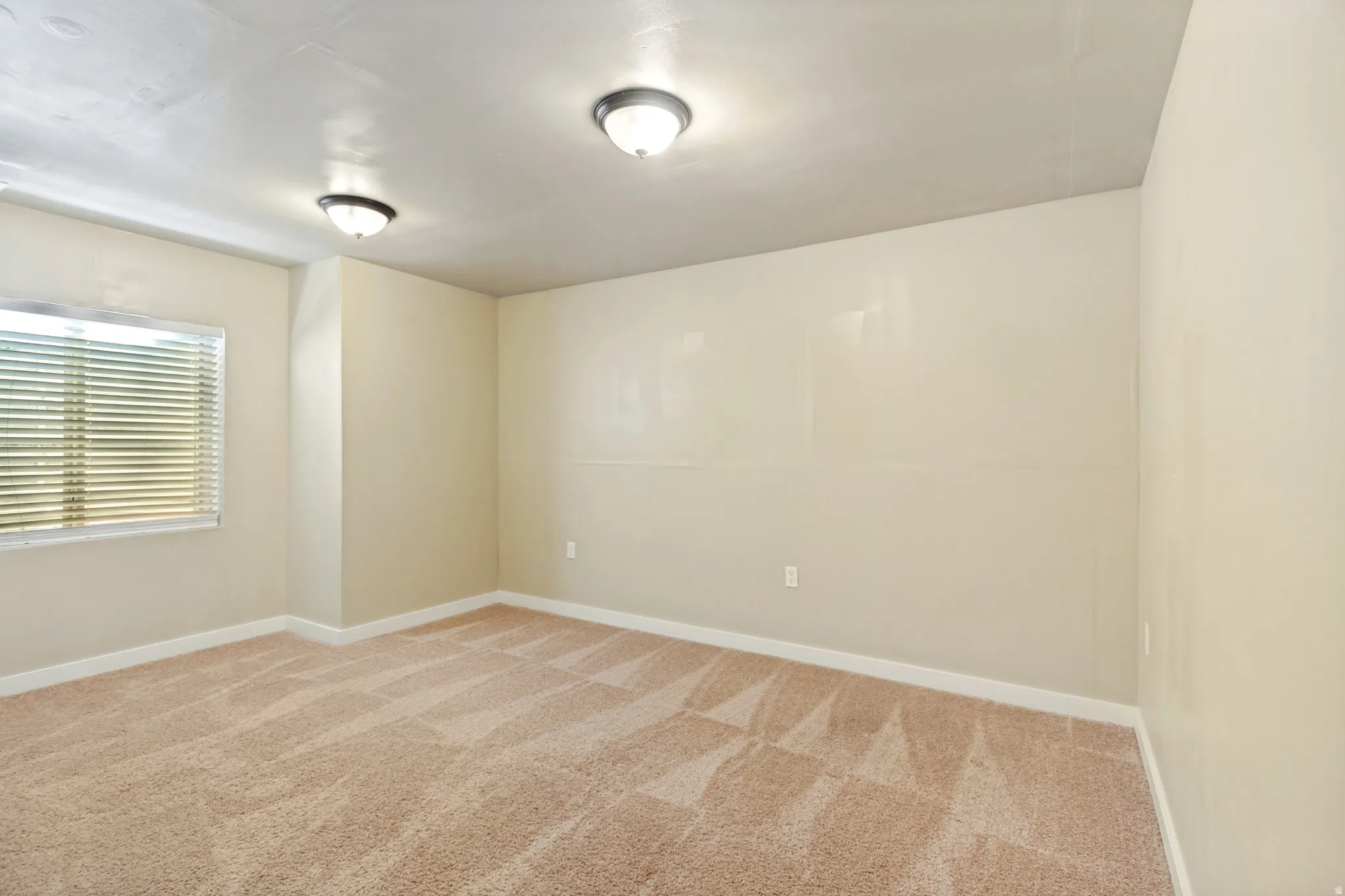 Neutral wall tones, recessed lighting, window with horizontal blinds, and carpeting