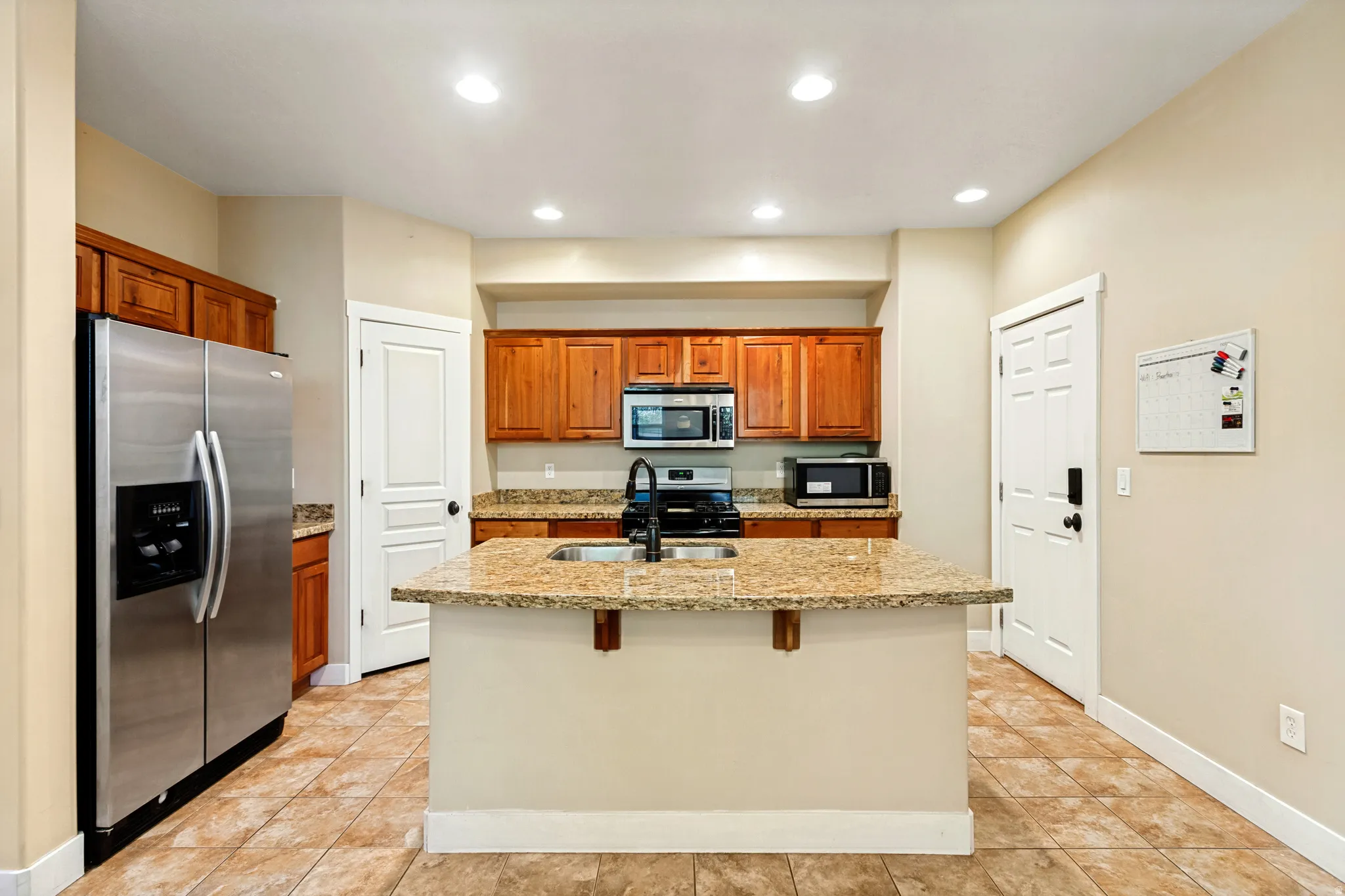 Kitchen featuring a center island with sink, wood cabinetry, stainless steel appliances, and recessed lighting