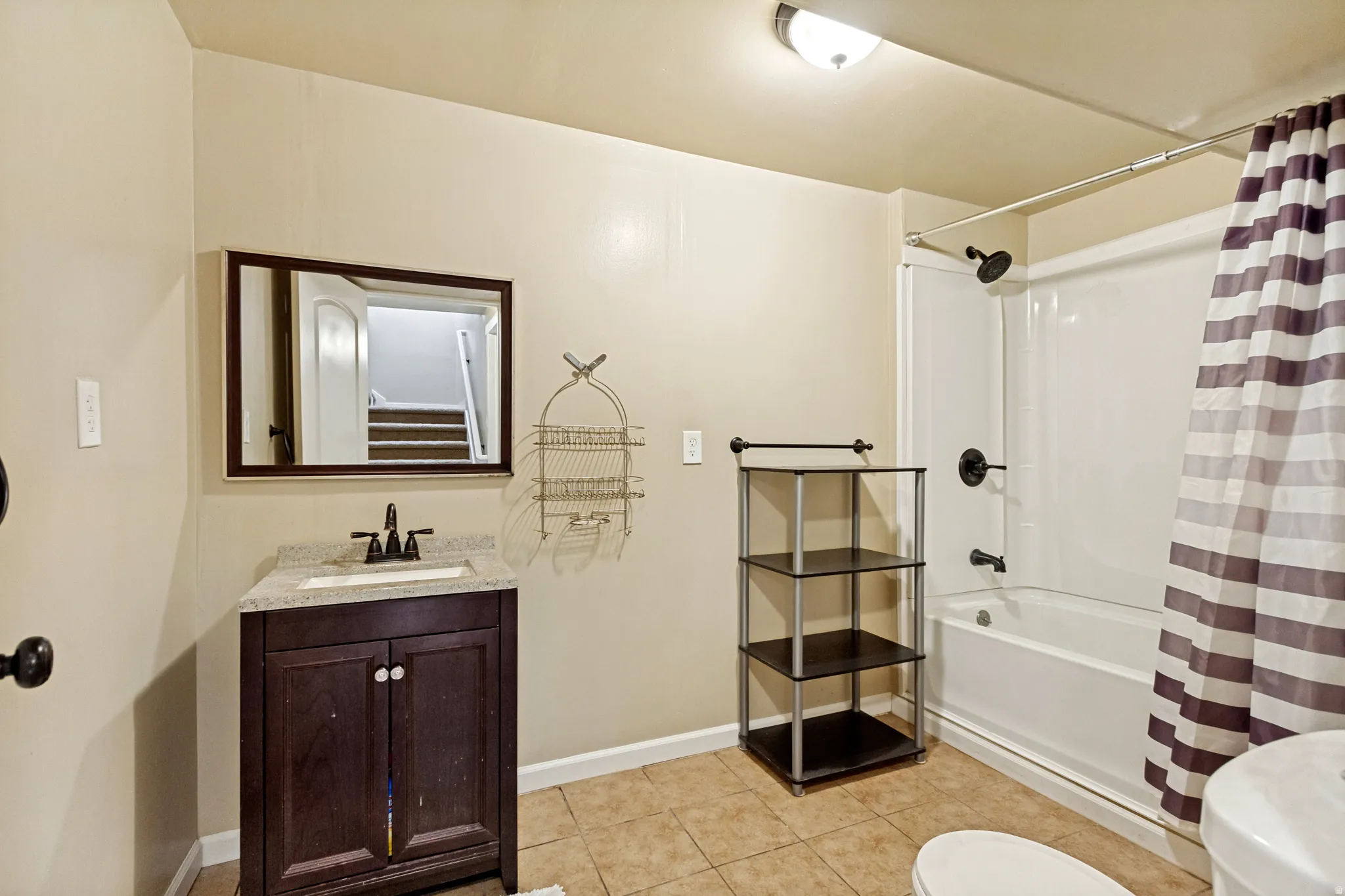 Bathroom featuring a dark wood finish vanity with a light-toned countertop, a white rectangular sink, and a shower-over-tub combination with dark-finish fixtures
