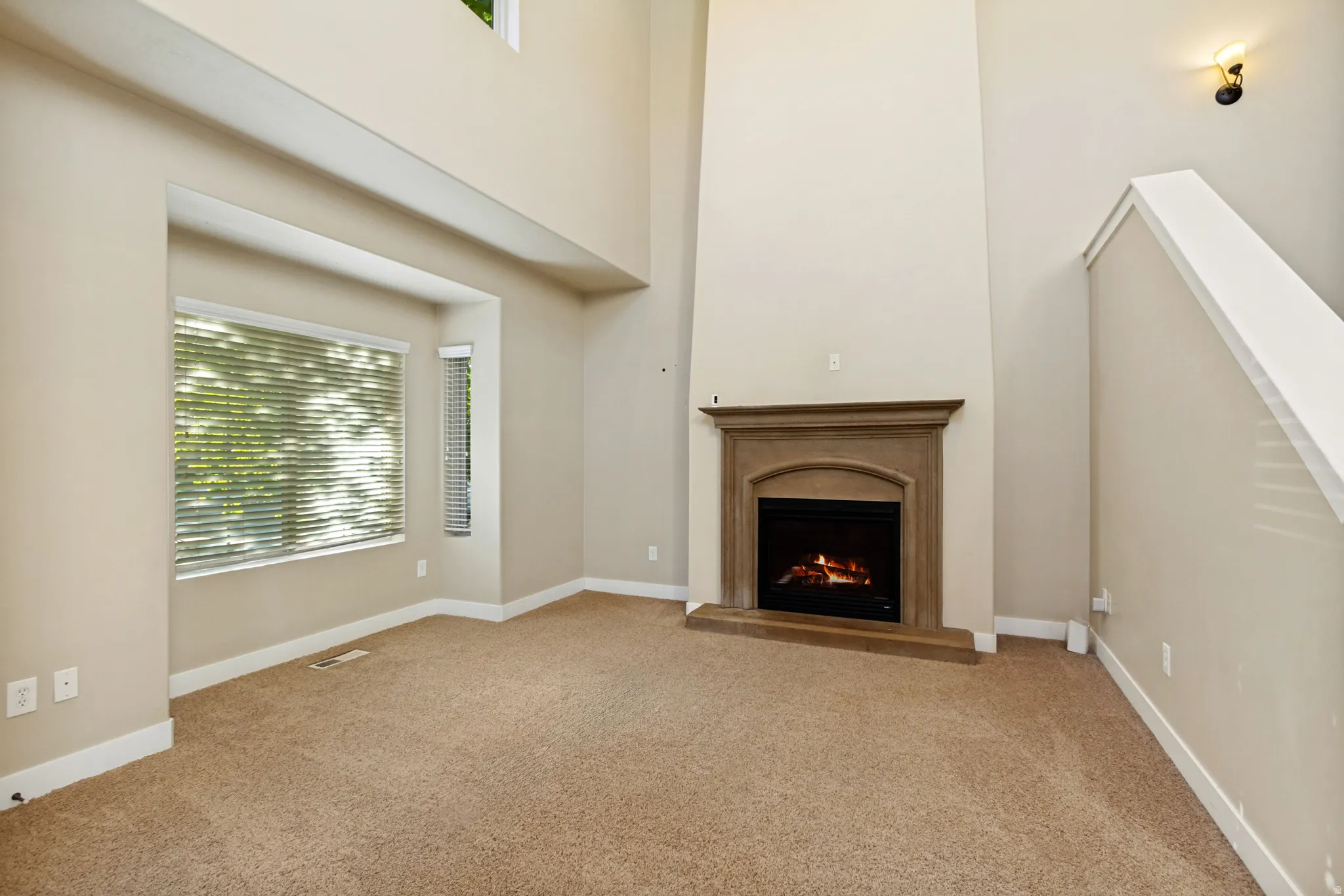 Two-story ceiling, bay window, built-in fireplace with a substantial mantel, and carpet flooring