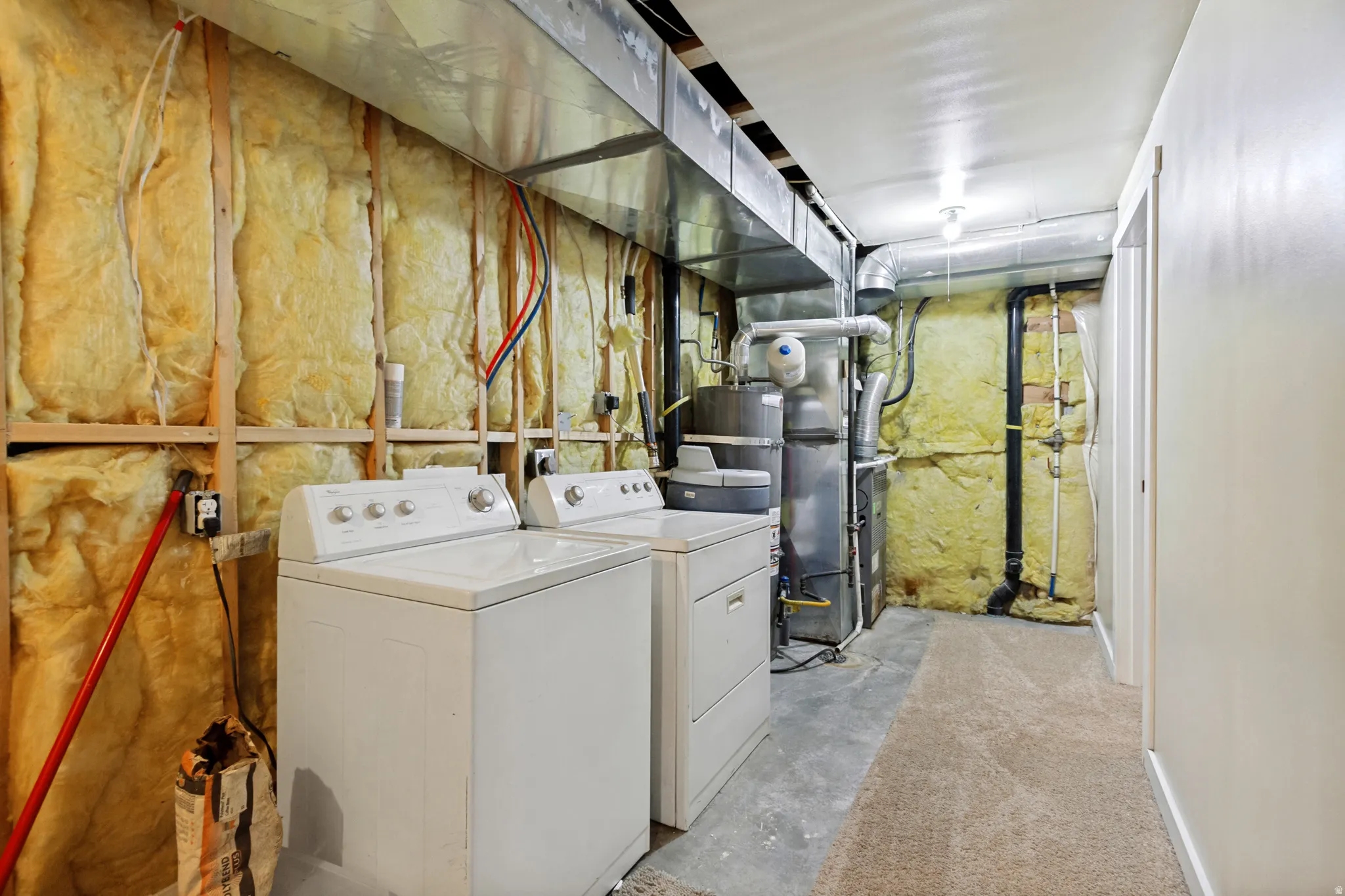 Utility room with exposed insulation, HVAC ductwork, and a water heater