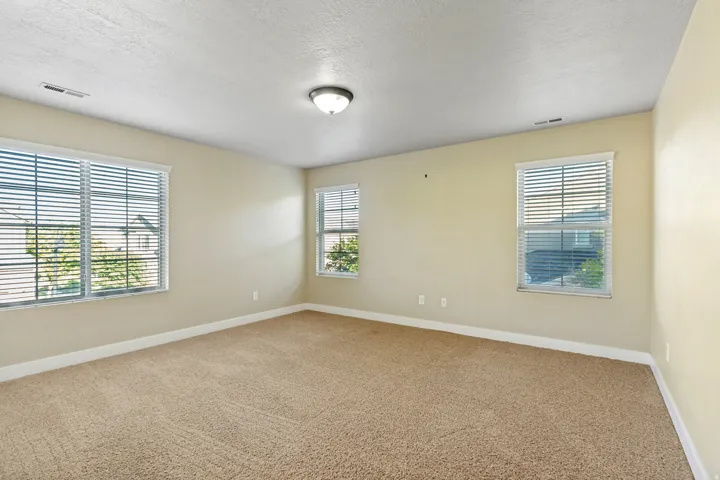 Carpeted flooring, three windows with horizontal blinds, flush mount ceiling light fixture, and neutral wall paint