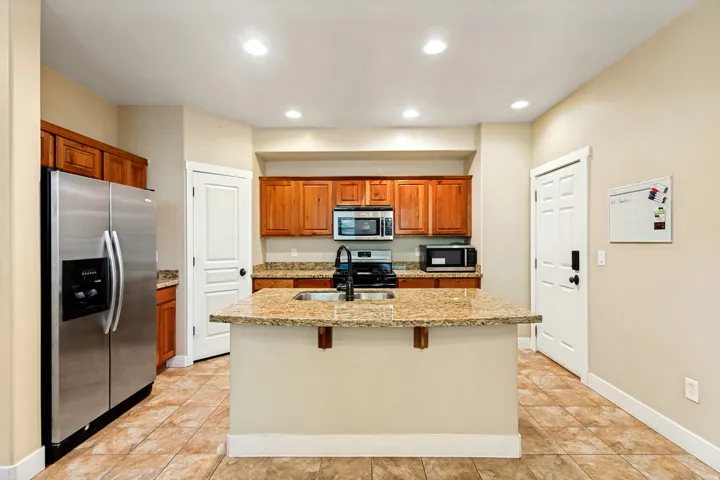 Kitchen featuring a center island with sink, wood cabinetry, stainless steel appliances, and recessed lighting
