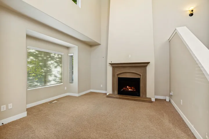 Two-story ceiling, bay window, built-in fireplace with a substantial mantel, and carpet flooring