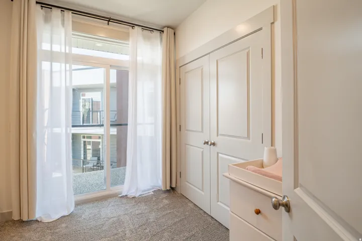 Sliding glass door with sheer and opaque curtains, double panel doors, and gray carpet flooring