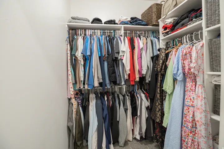 Custom closet system with multiple shelving tiers, integrated hanging rods, and corner shelving for optimized organization